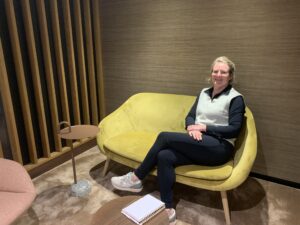 Cynthia zit op een bankje aan de rechterkant.