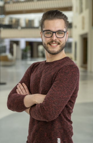 Roy staand in een gekruiste arm houden in een kantoorpand
